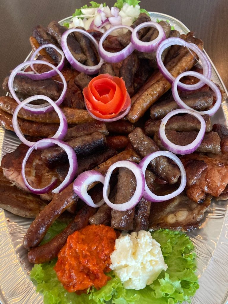 Ćevapi na kg Ćevapi na kilogram složeni na velikoj plati sa lukom, ajvarom i prilozima u Novom Sadu.