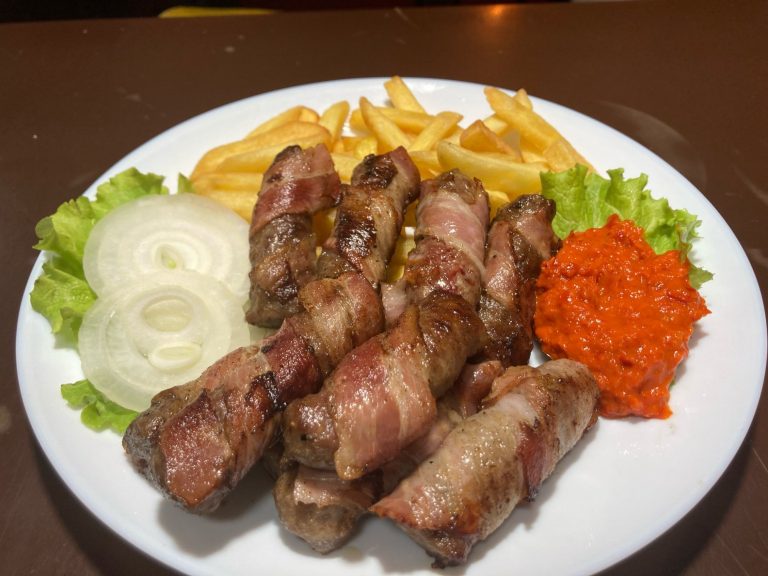 Rolovani ćevapi u slanini Rolovani ćevapi umotani u slaninu sa pomfritom, lukom i ajvarom u restoranu Dedina Tajna Novi Sad.